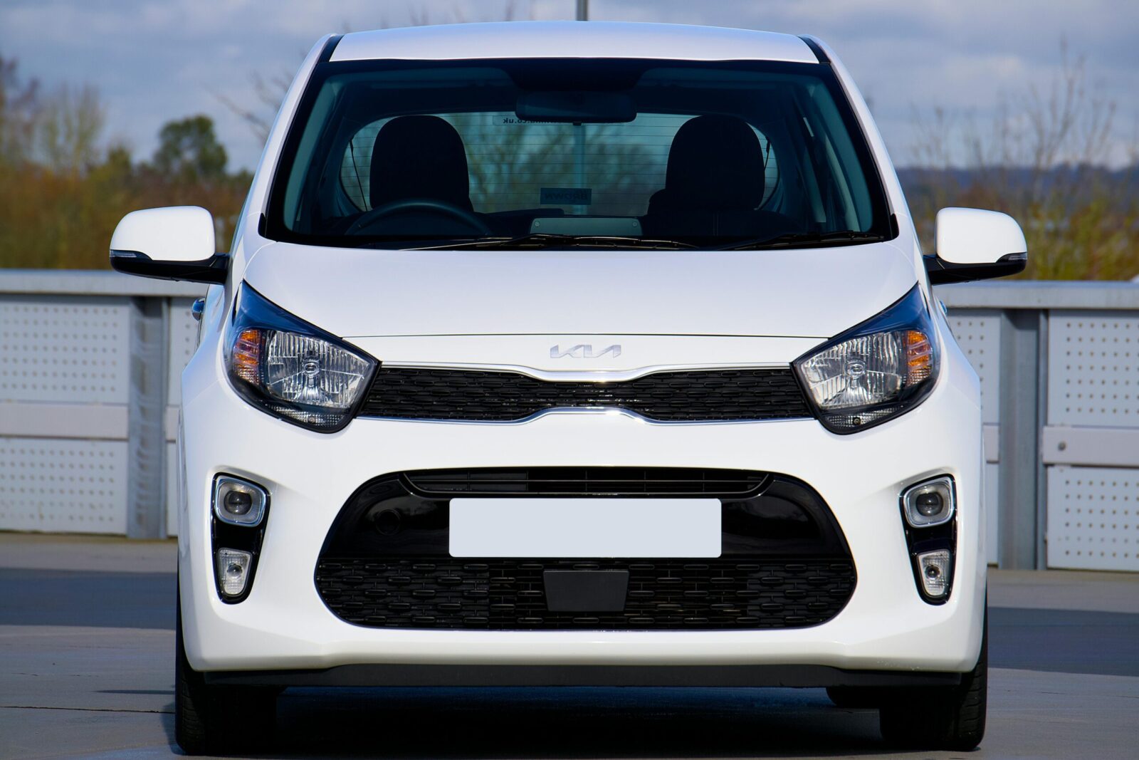 Sleek white Kia Picanto displayed in an outdoor parking area, Harlow, UK.