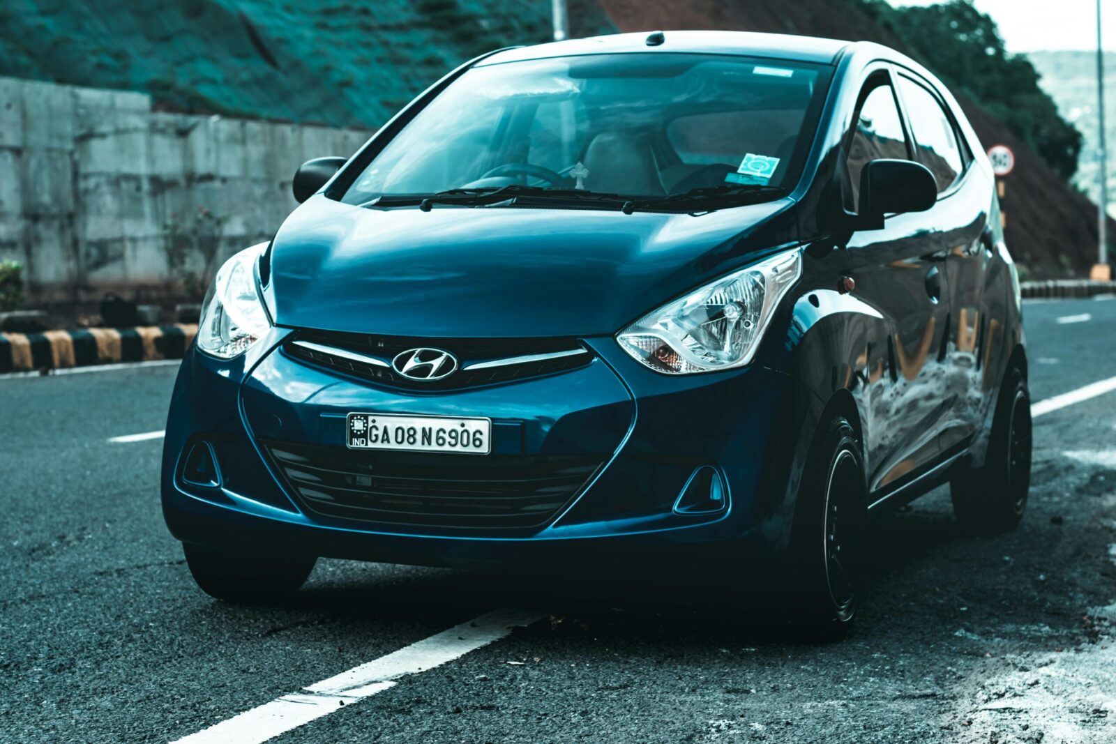 A vibrant blue Hyundai hatchback car parked on a scenic asphalt road, perfect for travel themes.
