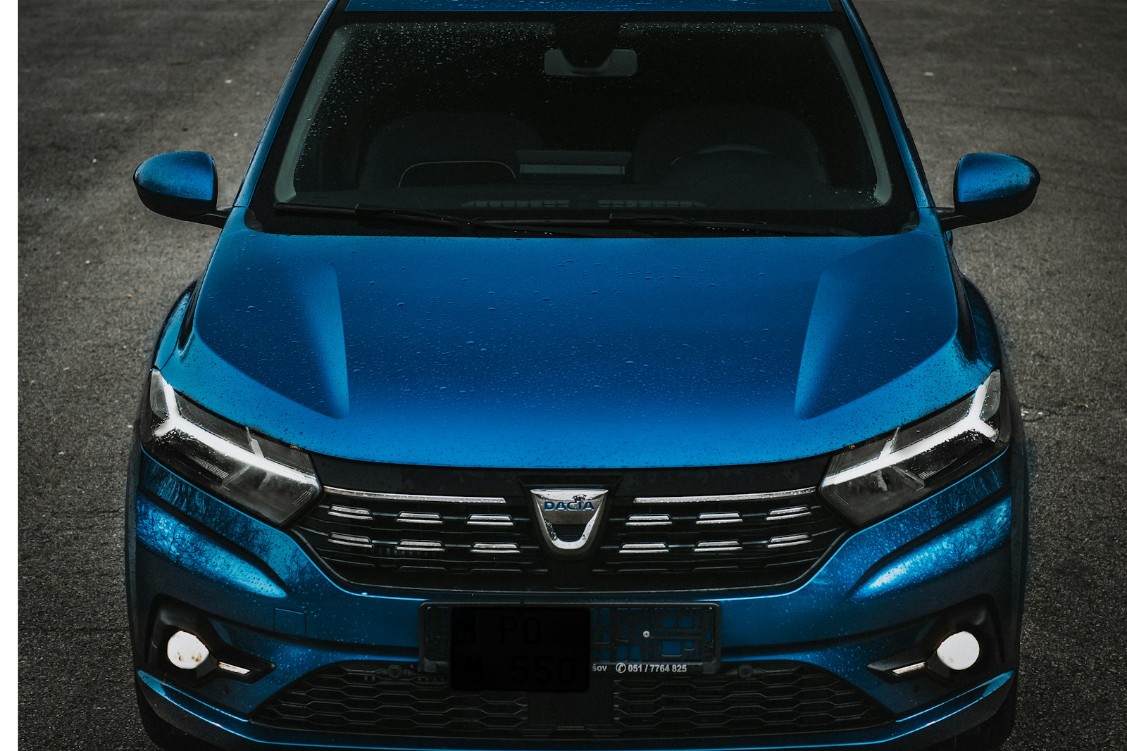 the front of a blue car parked in a parking lot